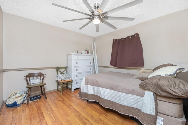 bedroom with light hardwood / wood-style floors, ceiling fan, and a textured ceiling