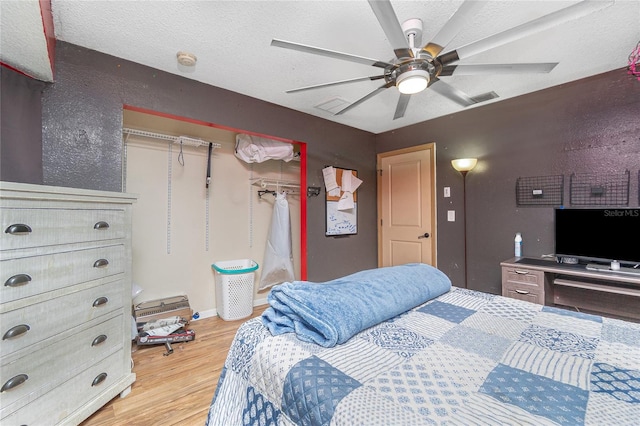 bedroom featuring a closet, hardwood / wood-style floors, ceiling fan, and a textured ceiling