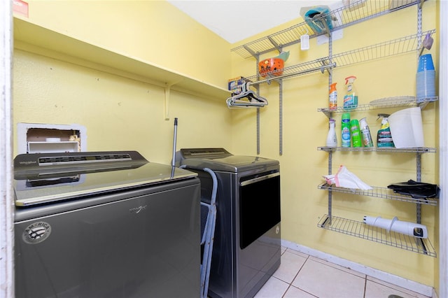 clothes washing area featuring washing machine and dryer and light tile patterned flooring