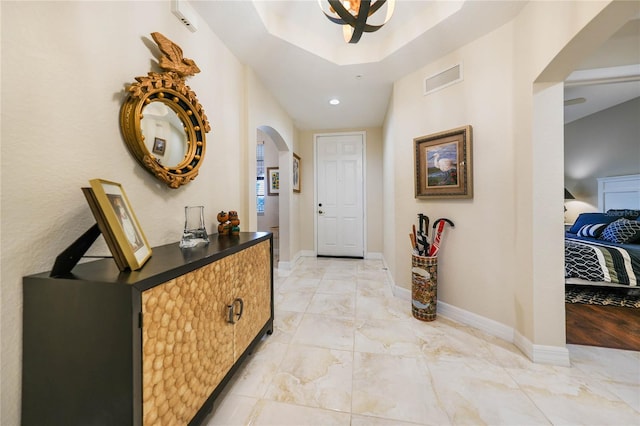 hall featuring marble finish floor, baseboards, visible vents, and arched walkways