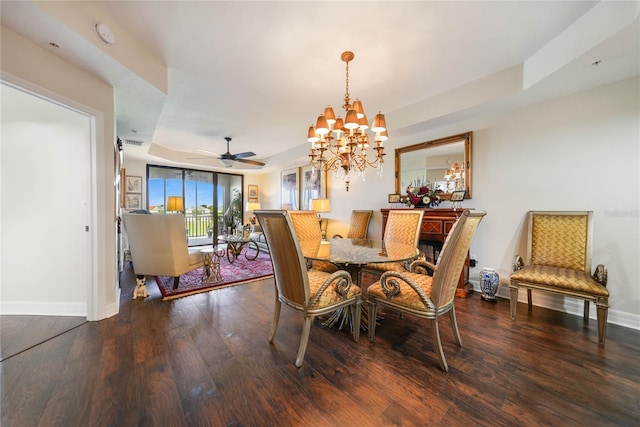 dining area with ceiling fan with notable chandelier, wood-type flooring, and a raised ceiling