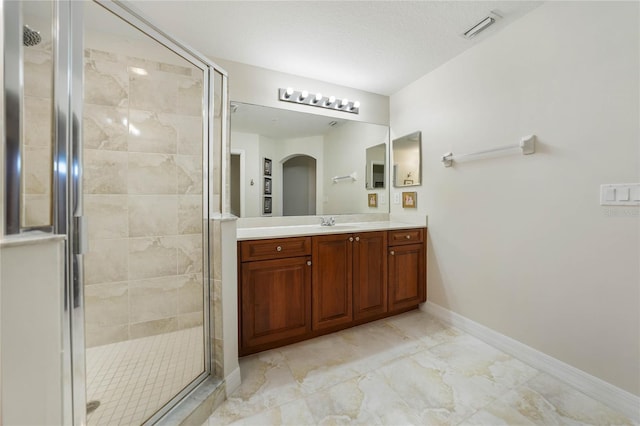 bathroom with baseboards, visible vents, a shower stall, and vanity