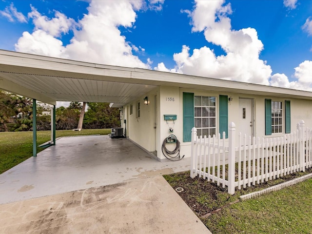 view of front of house with central AC, a carport, and a front yard