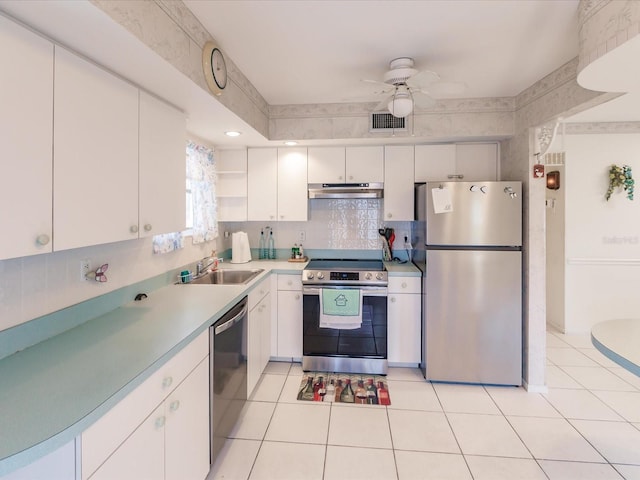 kitchen featuring appliances with stainless steel finishes, sink, light tile patterned floors, and white cabinets