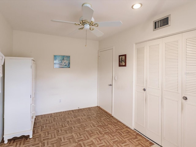 unfurnished bedroom with light parquet flooring, ceiling fan, and a closet