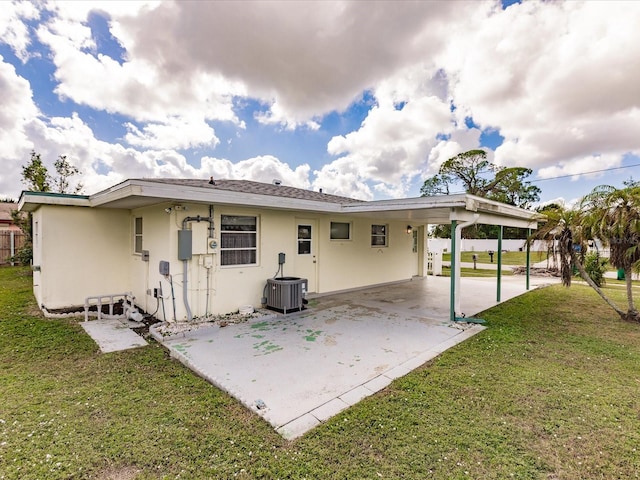 rear view of property featuring a yard, a carport, and central AC