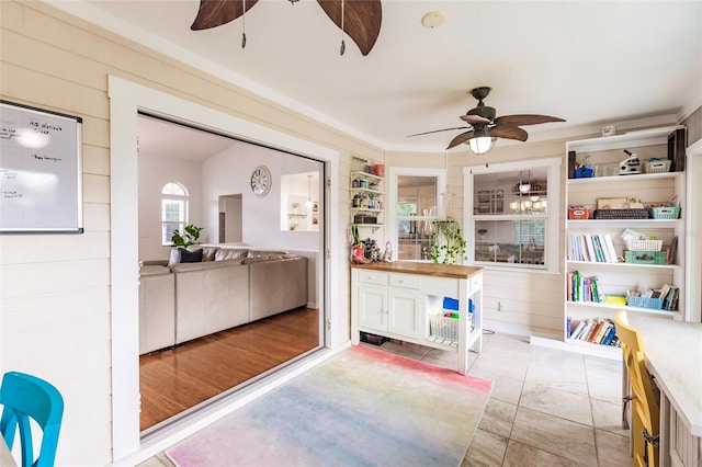 interior space with light hardwood / wood-style flooring, wooden walls, and ceiling fan