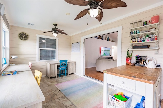 interior space featuring ceiling fan, wooden walls, and butcher block countertops