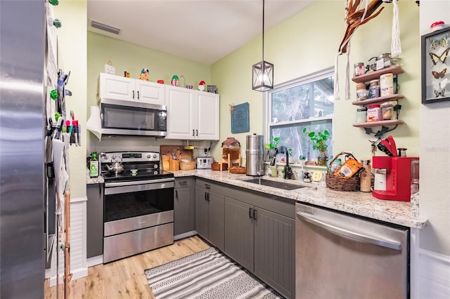 kitchen with stainless steel appliances, white cabinetry, sink, gray cabinetry, and light wood-type flooring