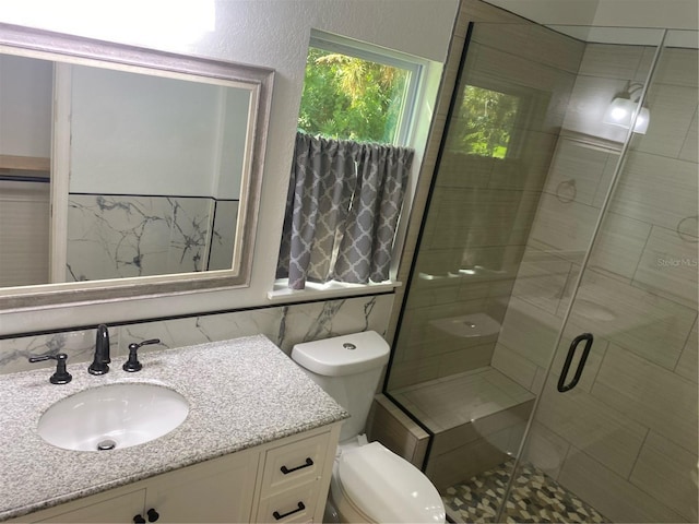 bathroom featuring toilet, tile walls, vanity, and a shower with shower door