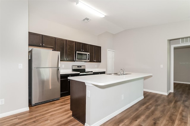 kitchen featuring appliances with stainless steel finishes, wood-type flooring, vaulted ceiling, and a center island with sink