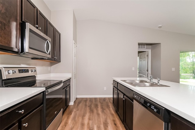 kitchen with light hardwood / wood-style floors, stainless steel appliances, vaulted ceiling, dark brown cabinetry, and sink