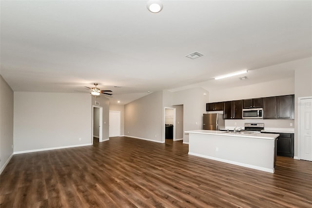 kitchen with appliances with stainless steel finishes, dark wood-type flooring, a center island with sink, and ceiling fan