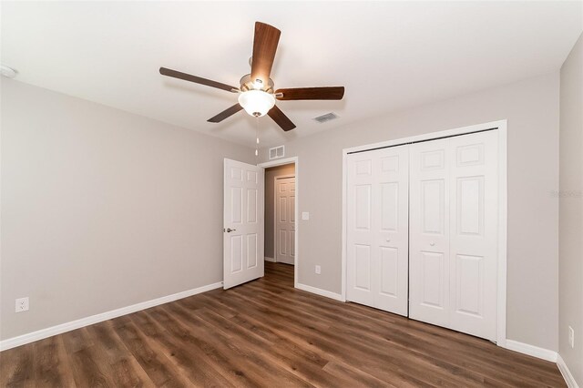 unfurnished bedroom with dark wood-type flooring, a closet, and ceiling fan