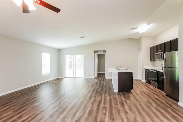 kitchen featuring hardwood / wood-style flooring, appliances with stainless steel finishes, ceiling fan, a kitchen island with sink, and vaulted ceiling