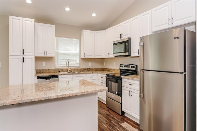 kitchen with stainless steel appliances, sink, light stone countertops, lofted ceiling, and white cabinets