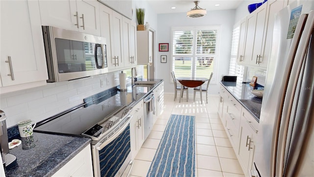 kitchen with stainless steel appliances, white cabinetry, sink, and light tile patterned floors