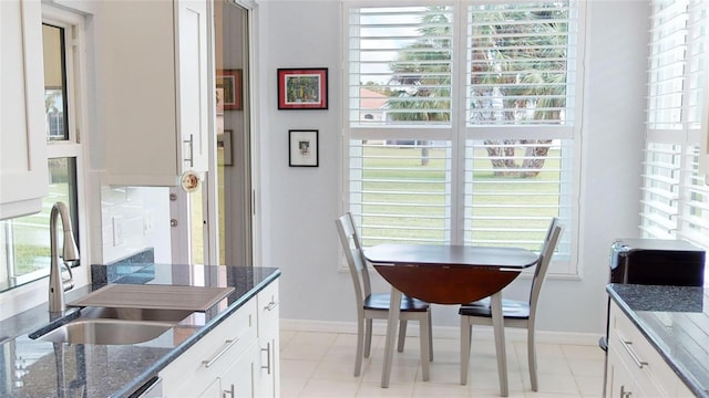 kitchen featuring white cabinetry, dark stone counters, a healthy amount of sunlight, and sink