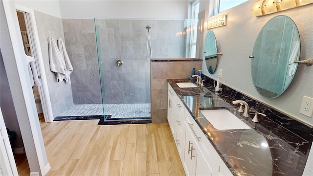 bathroom featuring wood-type flooring, vanity, toilet, and tiled shower