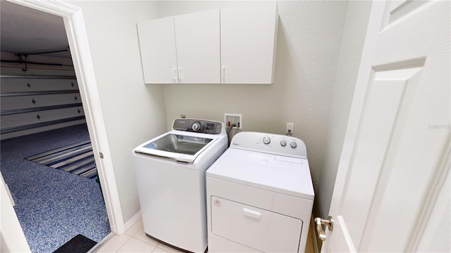 laundry area with cabinets, separate washer and dryer, and light tile patterned floors