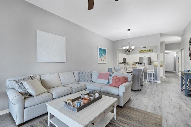 living room with light hardwood / wood-style floors and ceiling fan with notable chandelier