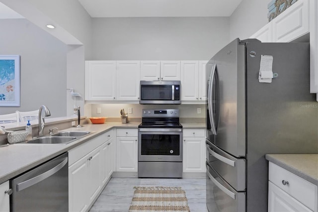 kitchen with white cabinets, appliances with stainless steel finishes, light hardwood / wood-style flooring, and sink