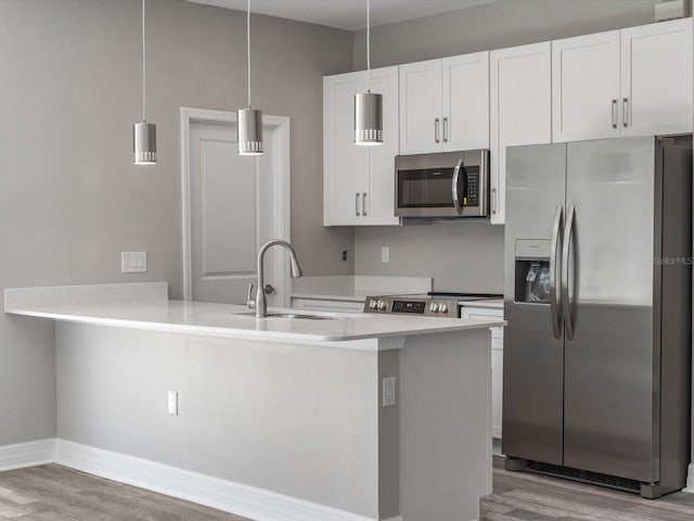 kitchen featuring stainless steel appliances, white cabinets, pendant lighting, and light hardwood / wood-style flooring