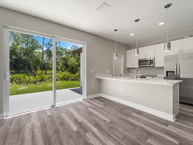 kitchen featuring stainless steel appliances, white cabinetry, decorative light fixtures, hardwood / wood-style flooring, and kitchen peninsula