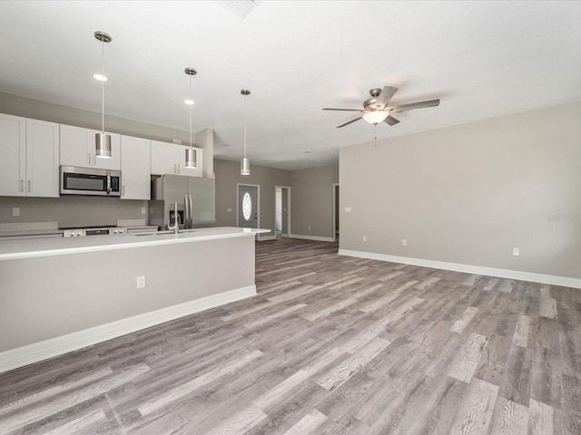 kitchen featuring appliances with stainless steel finishes, ceiling fan, light hardwood / wood-style flooring, white cabinets, and pendant lighting