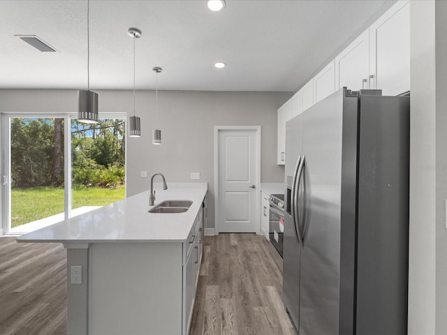 kitchen with stainless steel appliances, white cabinets, hardwood / wood-style flooring, sink, and decorative light fixtures