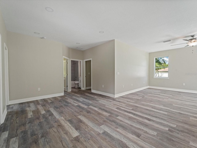 empty room with ceiling fan, wood-type flooring, and a textured ceiling