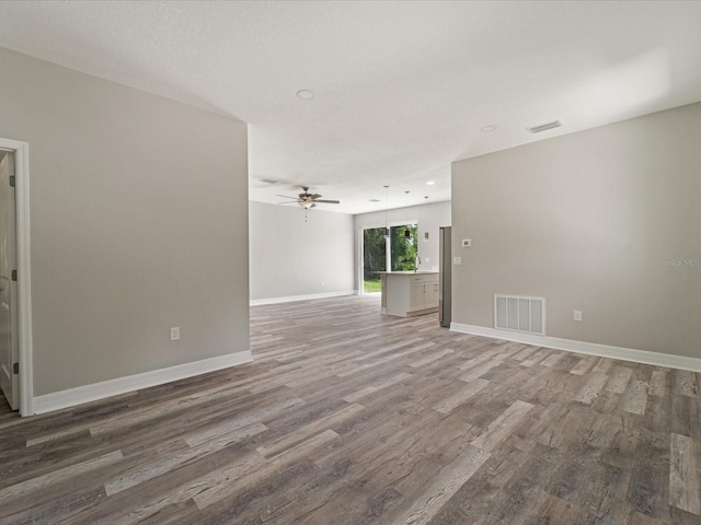 unfurnished living room with hardwood / wood-style flooring and ceiling fan