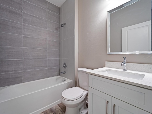 full bathroom featuring hardwood / wood-style floors, vanity, tiled shower / bath combo, and toilet