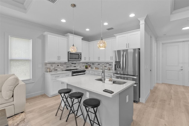 kitchen with white cabinetry, stainless steel appliances, hanging light fixtures, and light hardwood / wood-style flooring