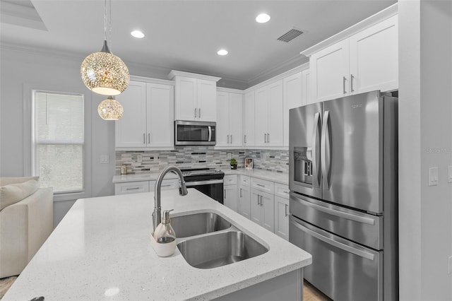 kitchen featuring white cabinetry, pendant lighting, appliances with stainless steel finishes, and ornamental molding