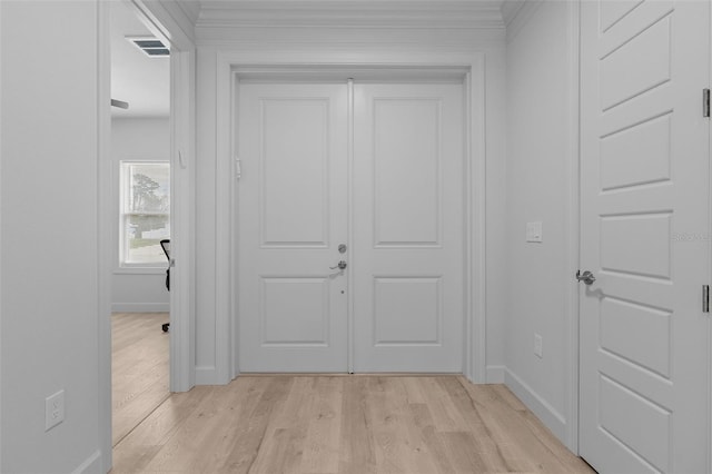 hall with ornamental molding and light wood-type flooring