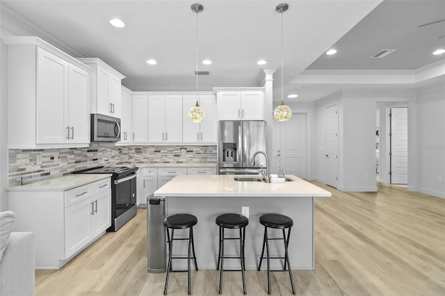 kitchen featuring light wood-type flooring, pendant lighting, white cabinets, and stainless steel appliances