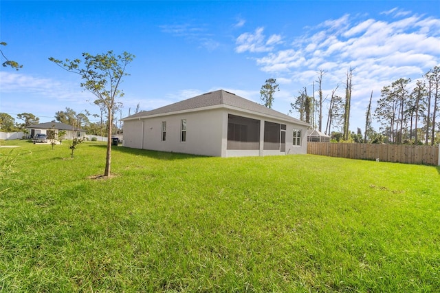 rear view of house with a sunroom and a lawn