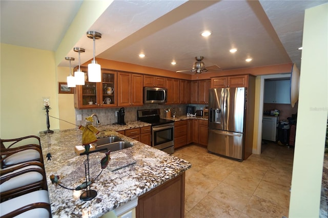 kitchen with ceiling fan, light stone counters, backsplash, kitchen peninsula, and appliances with stainless steel finishes