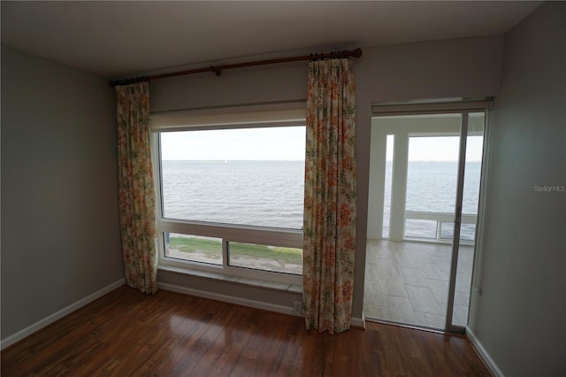 spare room featuring a water view and dark hardwood / wood-style floors