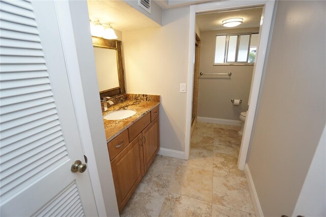 bathroom with vanity, a shower with shower door, and toilet