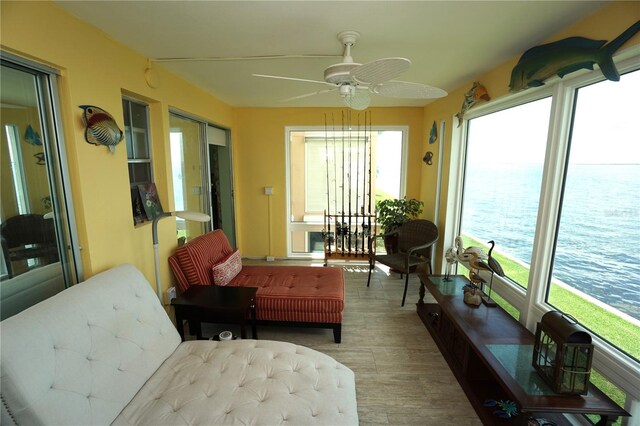 sunroom / solarium with ceiling fan and a water view