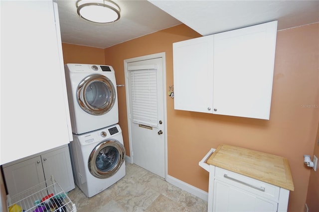 clothes washing area with cabinets and stacked washer / drying machine