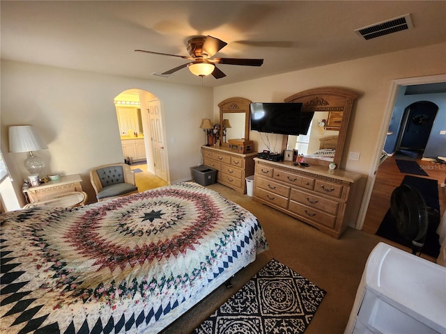 bedroom with light colored carpet, ceiling fan, and ensuite bath