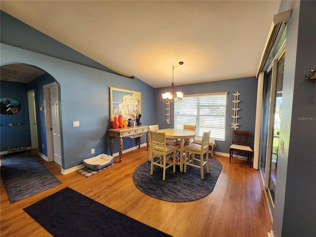 dining space with hardwood / wood-style floors, an inviting chandelier, and lofted ceiling