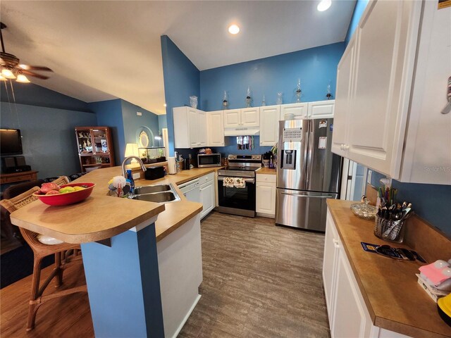 kitchen featuring white cabinetry, sink, kitchen peninsula, appliances with stainless steel finishes, and dark hardwood / wood-style flooring