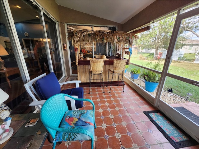 sunroom / solarium featuring bar area and lofted ceiling