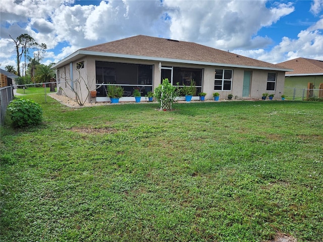 rear view of property with a lawn and a sunroom