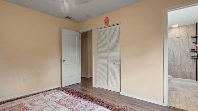 unfurnished bedroom with ensuite bath, a closet, and wood-type flooring