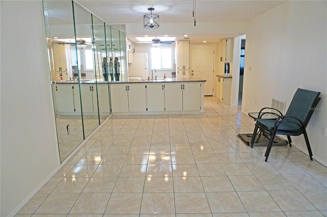 kitchen featuring light tile patterned flooring, white refrigerator, sink, white cabinets, and ceiling fan